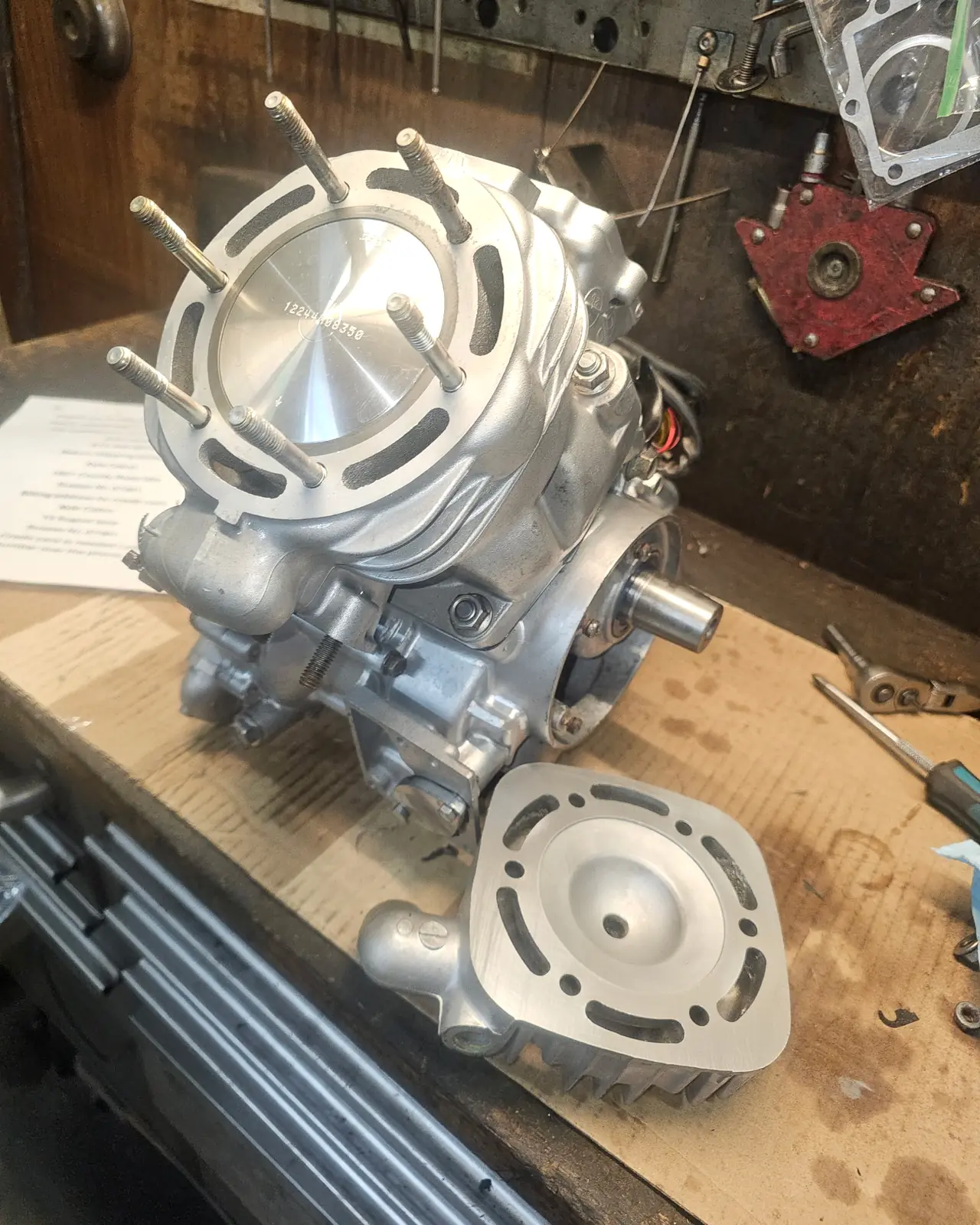 Rebuilt Polaris 2-stroke motor with a new piston in the bored cylinder and the machined head beside it
