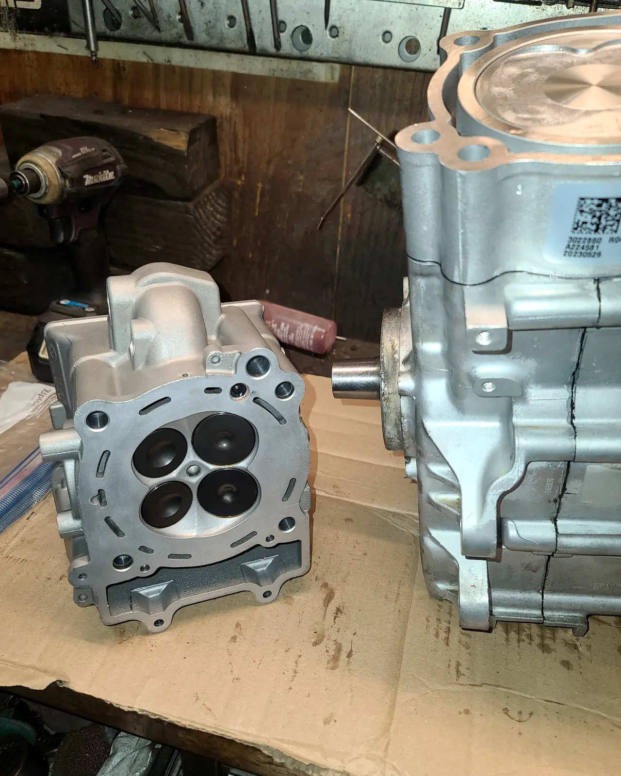 Machined Polaris cylinder head with its valve pockets exposed, beside an engine case