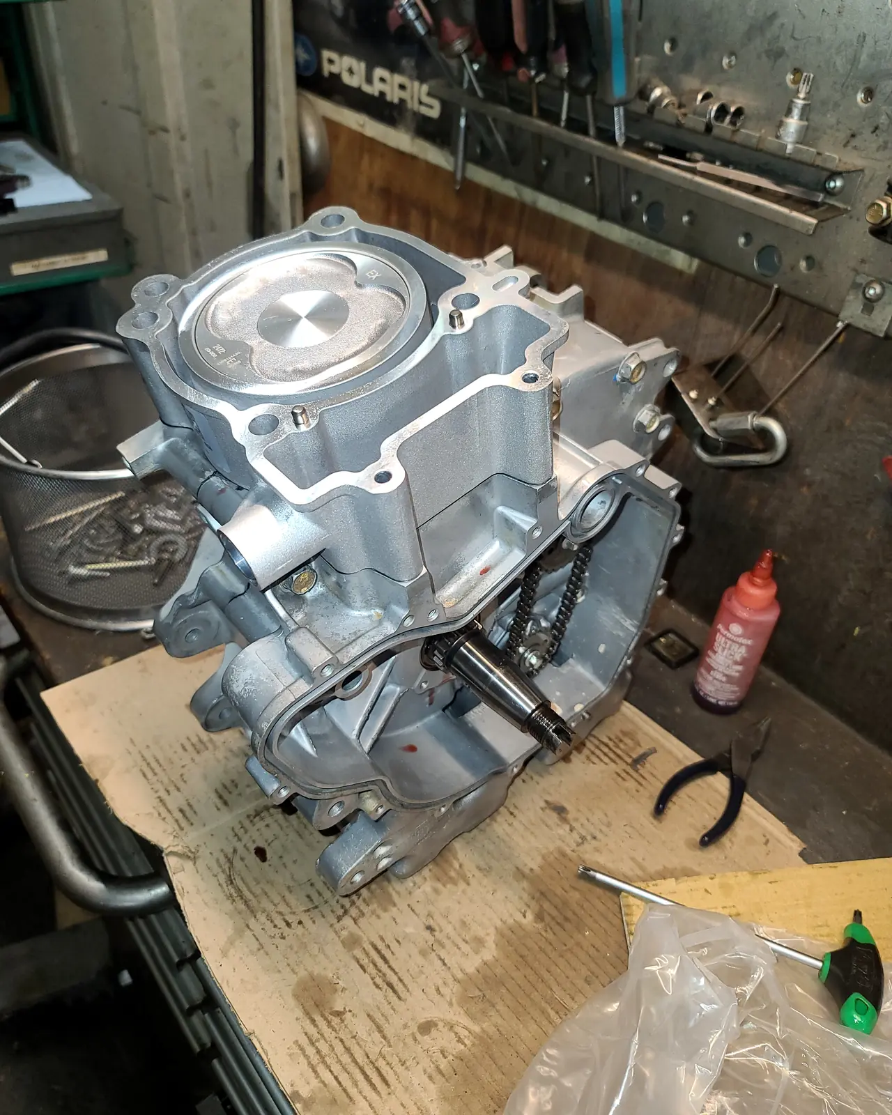Polaris engine case with the cylinder head fitted, on the bench beneath the Polaris sign