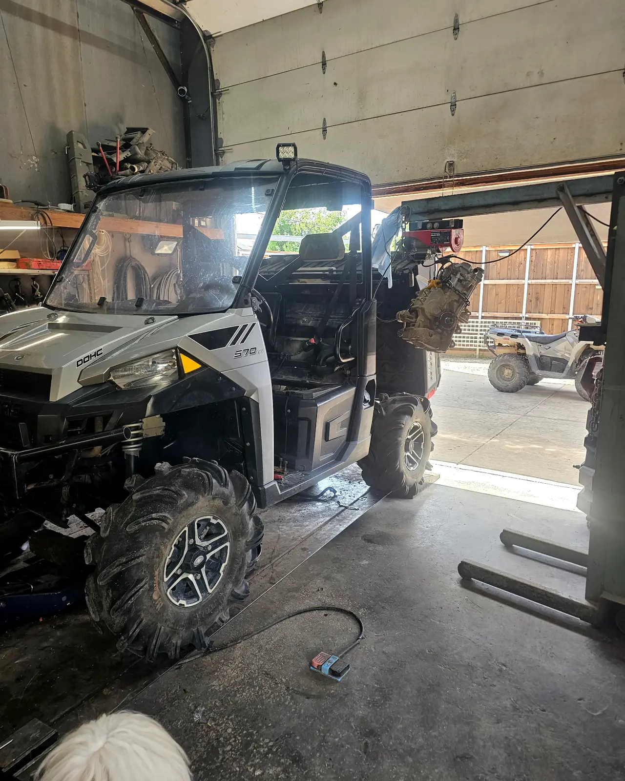 Polaris Ranger 570 EFI in the shop bay with its complete motor lifted out on the hoist