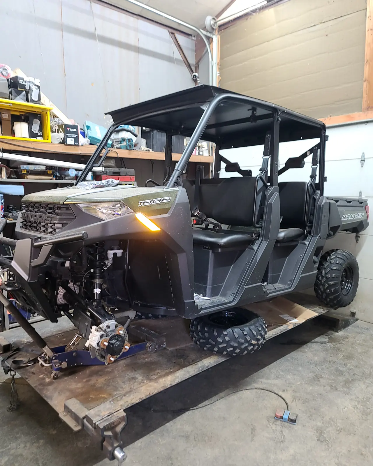 Polaris Ranger Crew up on stands in the shop with its headlights on, mid-service